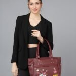 Women’s maroon tote handbag with floral embroidery and multiple zipper pockets